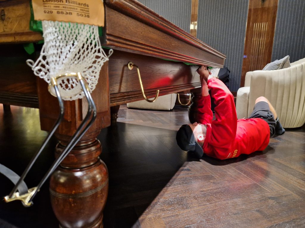 Oneplace2save team member dismantling a pool table by removing fixings underneath for safe removal