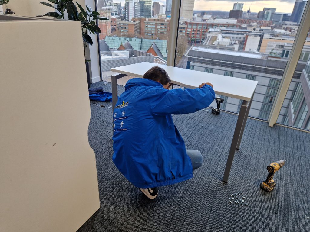 Oneplace2save team member dismantling an office desk with screws and tools ready for relocation
