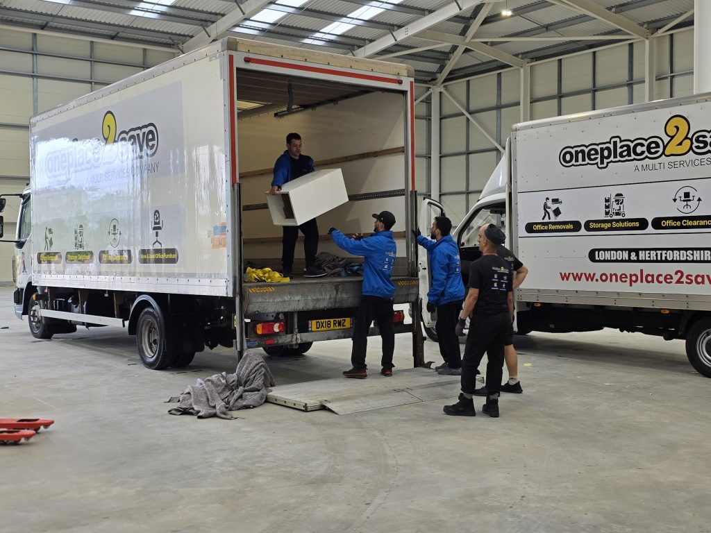 Oneplace2save team unloading a truck in a warehouse, moving a cabinet from the lorry during a removals job.