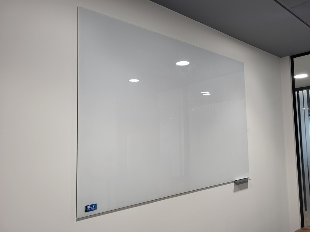 Office whiteboard positioned beside a project collaboration table
