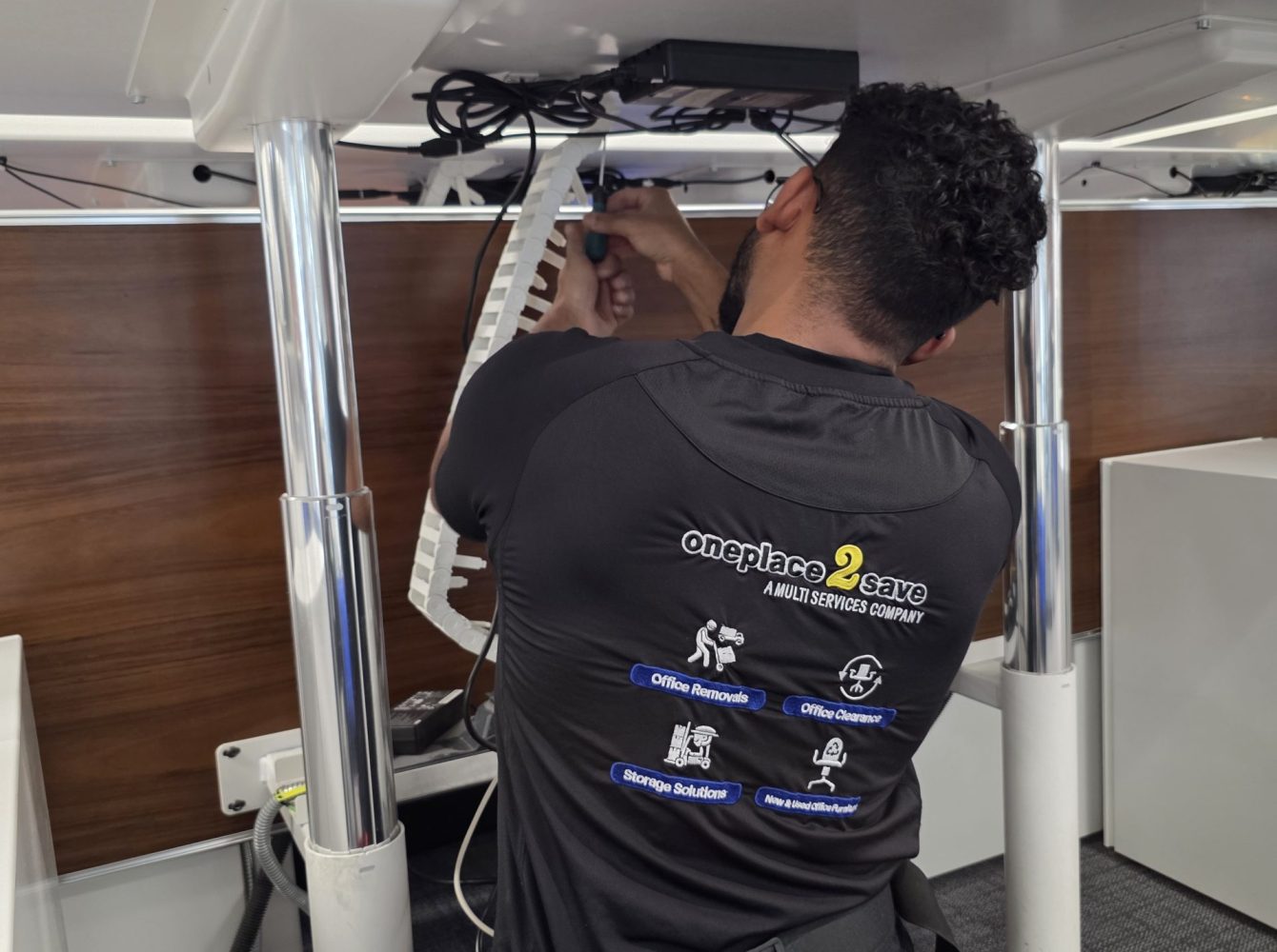 Cable management under an office desk as a oneplace2save operative secures cables for an office relocation